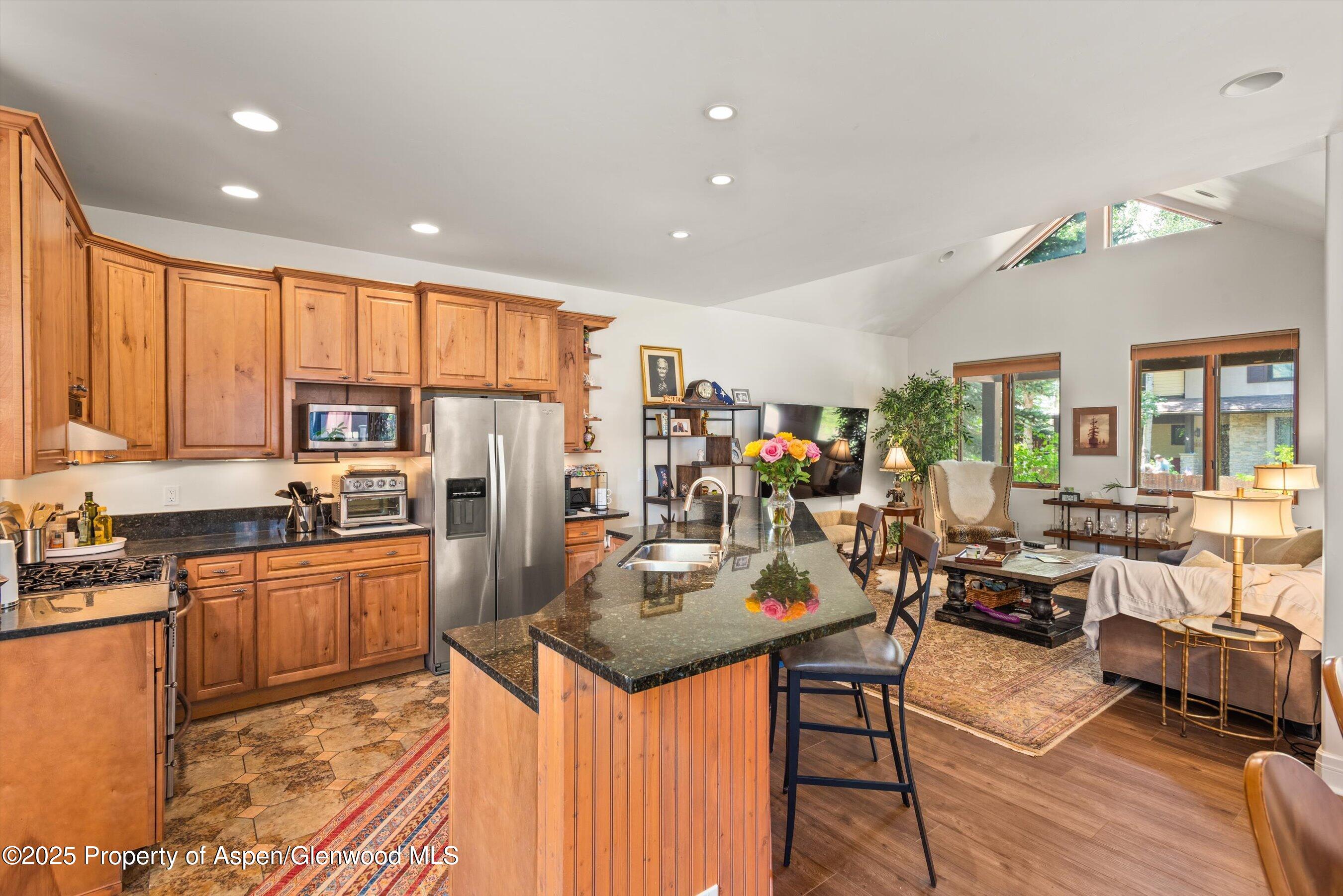 315 Summerset Lane, Unit A Basalt, CO 81621 - Photo 4 of 18 a kitchen with stainless steel appliances granite countertop a refrigerator a stove top oven a sink dishwasher and chairs with wooden floor