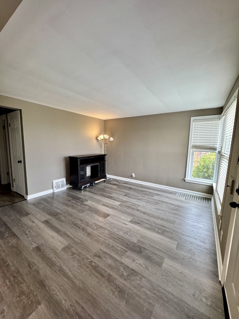 11042 South State Line Road Chicago, IL 60617 - Photo 3 of 12 a view of empty room with wooden floor and window