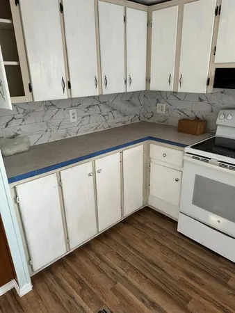 a kitchen with stainless steel appliances granite countertop a stove a sink and white cabinets