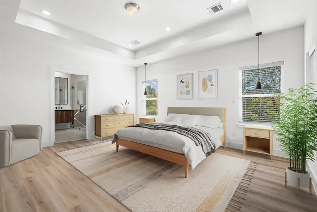 a spacious bedroom with a large bed a chandelier and windows