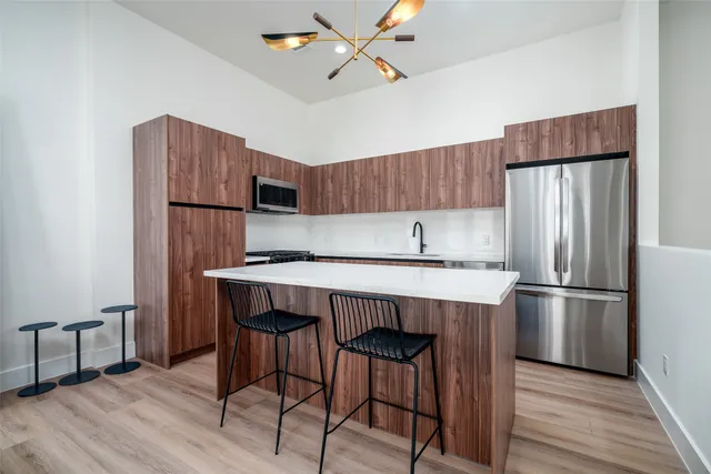 a kitchen with kitchen island a refrigerator stove and wooden floor