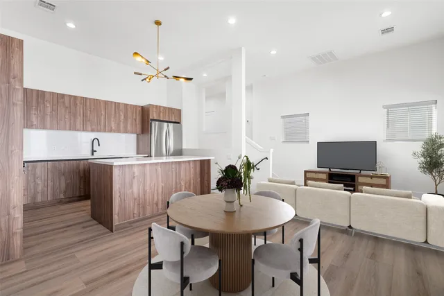 a kitchen with a table chairs a sink dishwasher refrigerator and cabinets with wooden floor