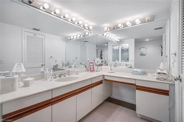 a large white kitchen with a sink and a mirror