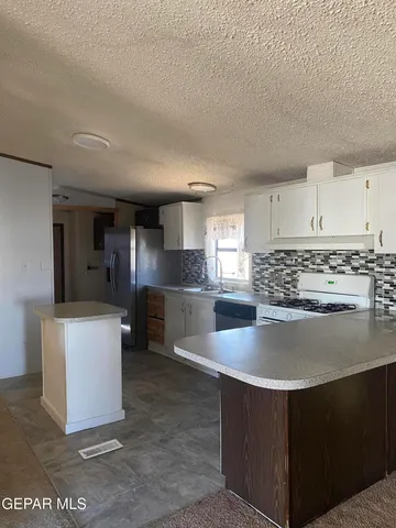 a view of kitchen with stainless steel appliances granite countertop a stove and a sink