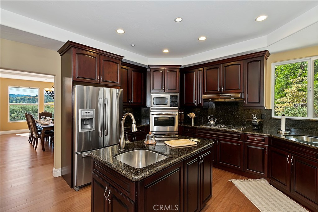 a kitchen with kitchen island granite countertop a sink stove refrigerator and cabinets