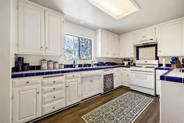 601 Neptune Avenue Encinitas, CA 92024 - Photo 18 of 36 a kitchen with granite countertop white cabinets and white appliances