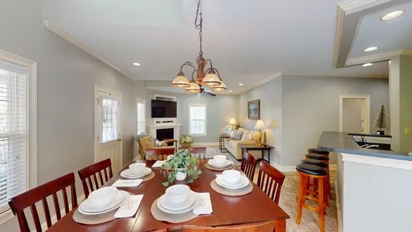 a dining room with wooden floor a chandelier a wooden table and chairs