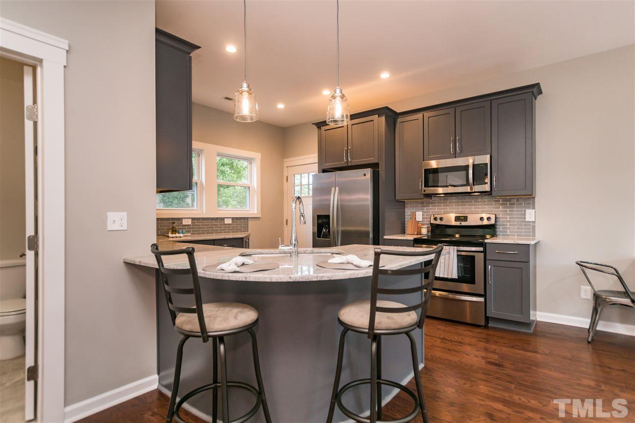 830 East Martin Street Raleigh, NC 27601 - Photo 8 of 24 a kitchen with stainless steel appliances kitchen island granite countertop a stove a refrigerator a sink a dining table and chairs with wooden floor
