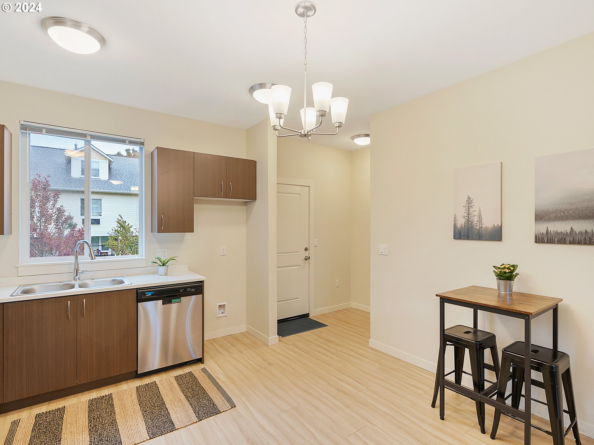 10827 East Burnside Street Portland, OR 97216 - Photo 10 of 28 a kitchen with stainless steel appliances granite countertop a refrigerator a sink dishwasher a dining table and chairs with wooden floor