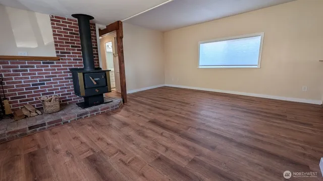 a view of an empty room with wooden floor and a fireplace