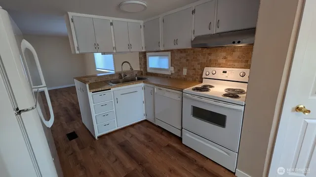a kitchen with granite countertop white cabinets and white appliances