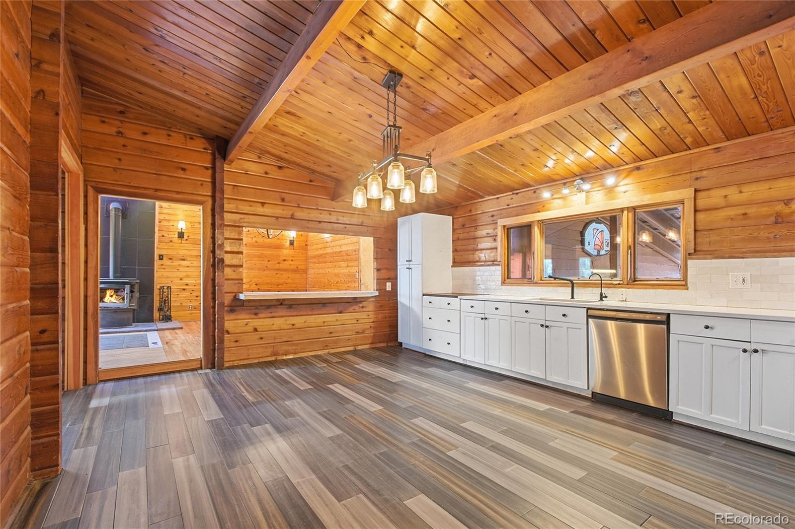 61 Ramona Road Golden, CO 80403 - Photo 18 of 49 a kitchen with granite countertop a stove a sink and white cabinets with wooden floor