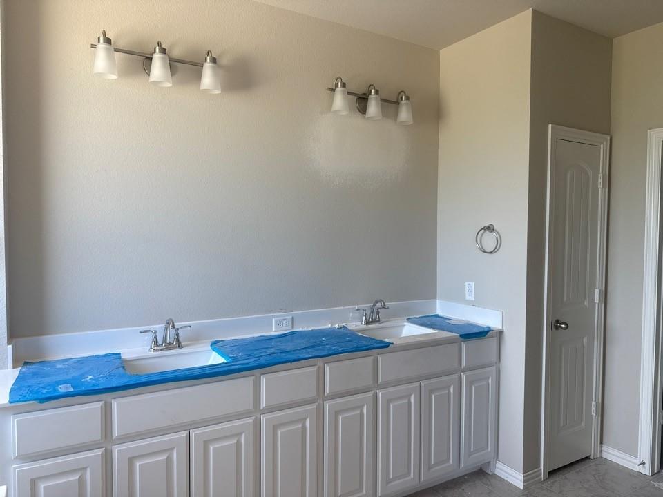 1228 Colca Drive Springtown, TX 76082 - Photo 7 of 9 Dual vanity with white shaker-style cabinetry, integrated sinks, and chrome faucets