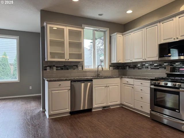 a kitchen with stainless steel appliances granite countertop a stove a sink and white cabinets