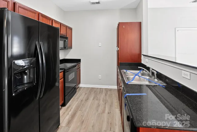 a view of a room with wooden floor ceiling fan and kitchen view