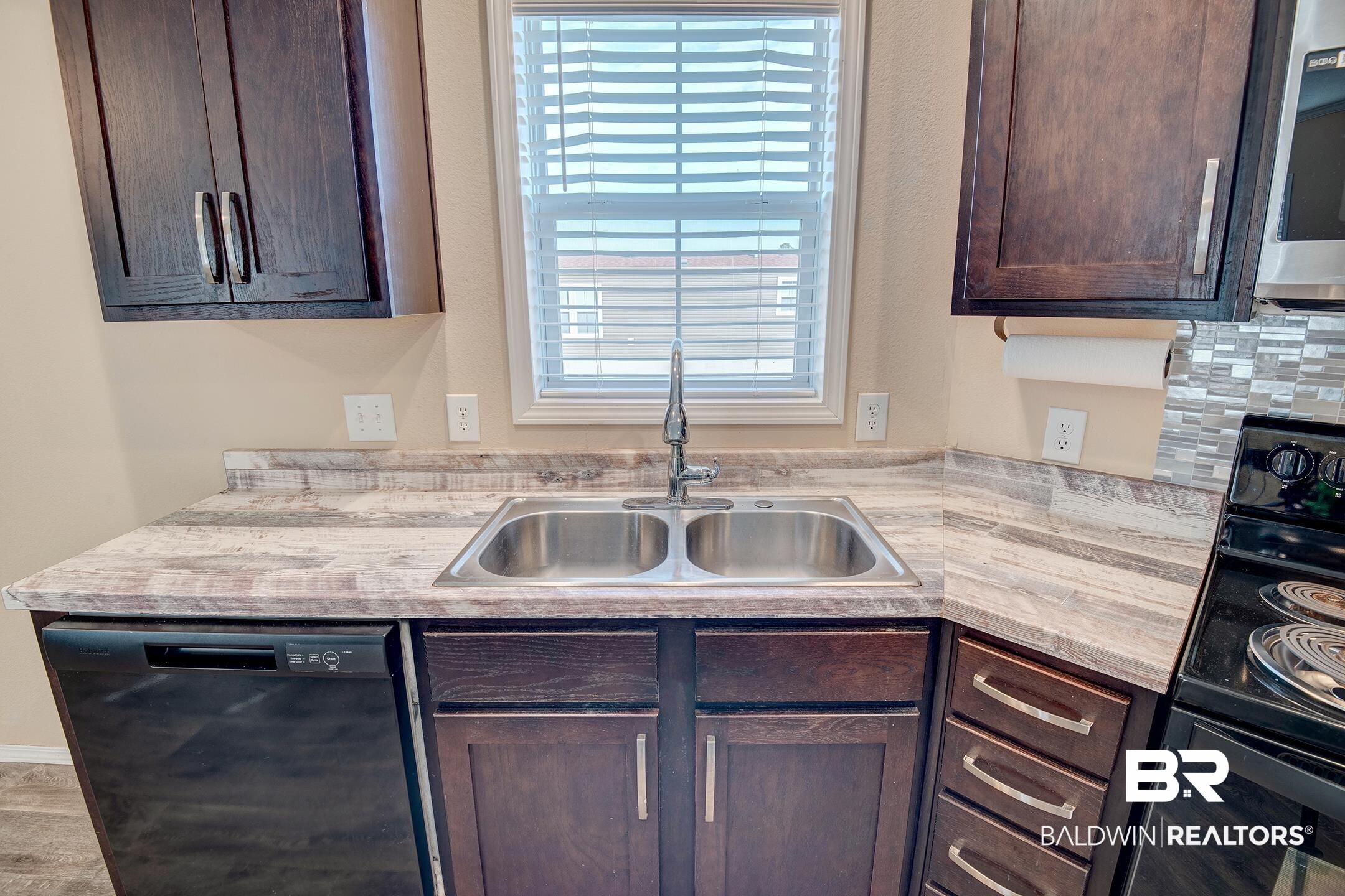 21859 West Side Loop Silverhill, AL 36576 - Photo 16 of 24 Kitchen with a healthy amount of sunlight, black appliances, dark brown cabinets, and sink