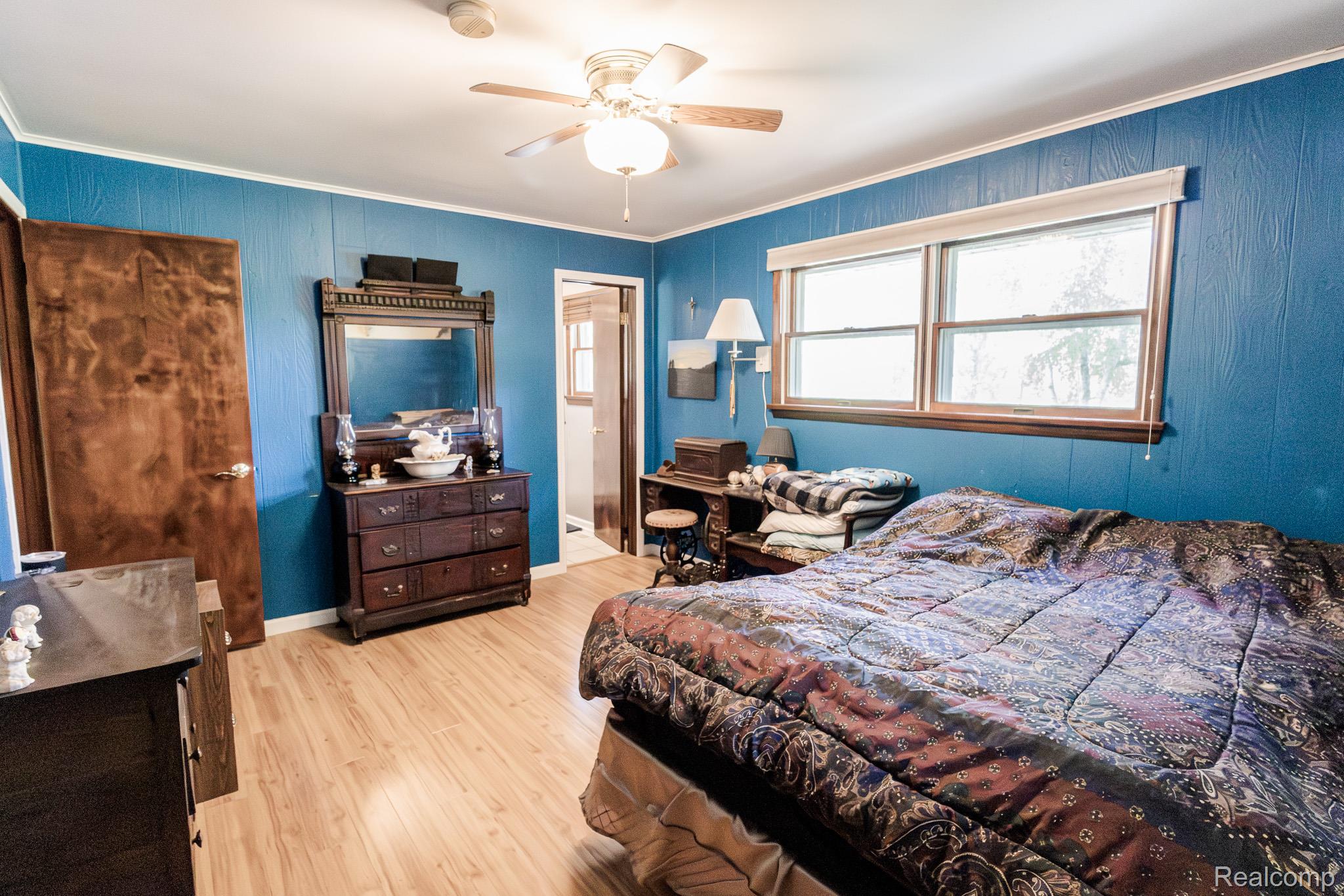 8197 Irish Road Millington, MI 48746 - Photo 21 of 38 Room featuring wood-finish flooring, blue wall paneling, and a ceiling fan with integrated lighting