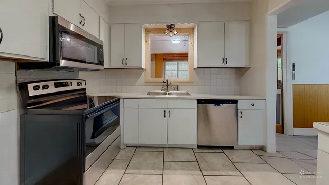 a kitchen with white cabinets a sink dishwasher and a stove with wooden floor