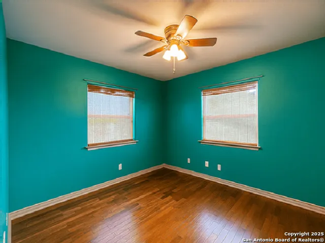 a view of an empty room with window and chandelier fan