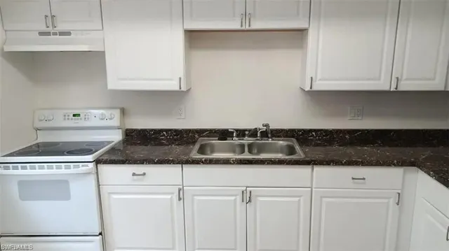 a kitchen with granite countertop white cabinets and white appliances