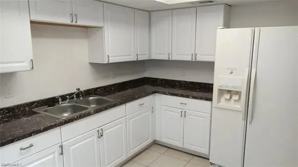 a kitchen with granite countertop white cabinets and refrigerator