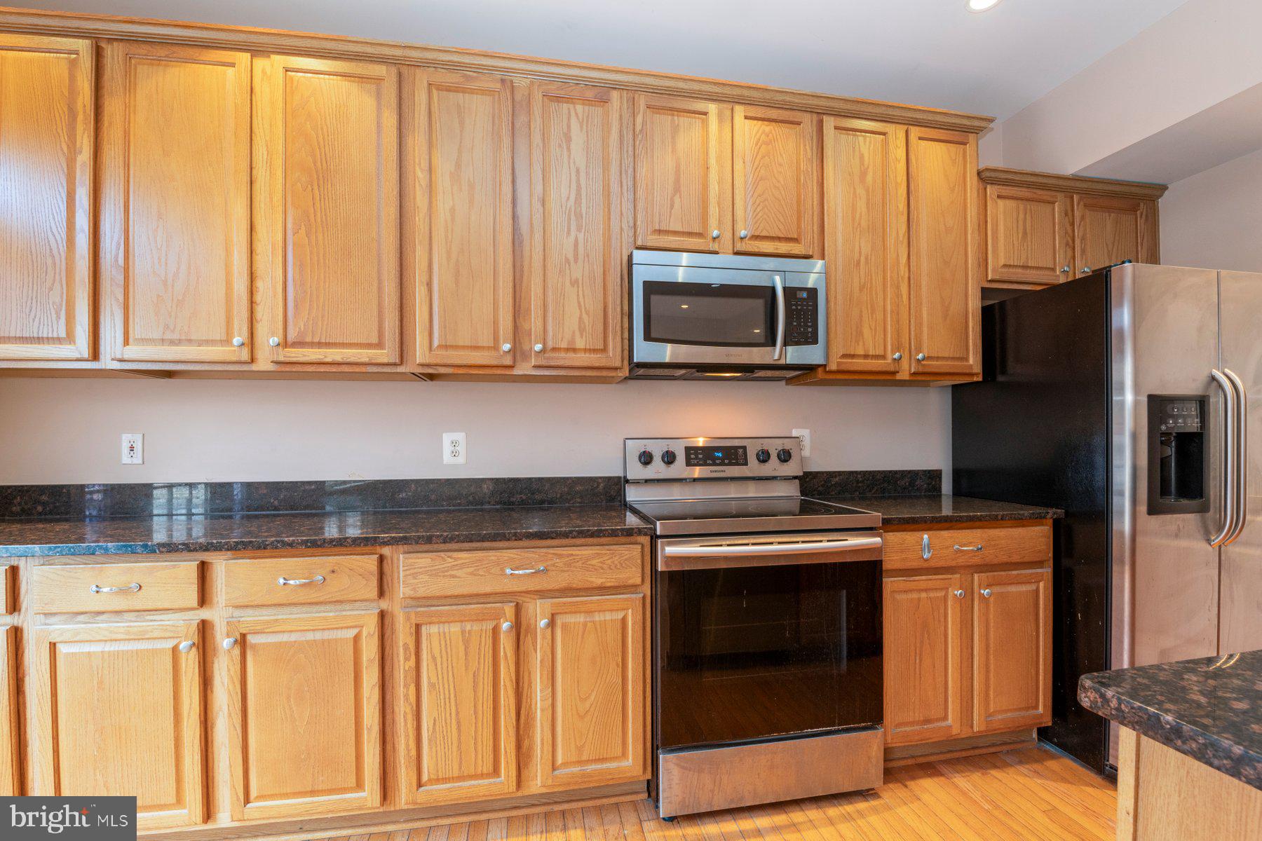 12802 Brightwell Drive Clarksburg, MD 20871 - Photo 11 of 30 a kitchen with granite countertop a stove top oven microwave and refrigerator