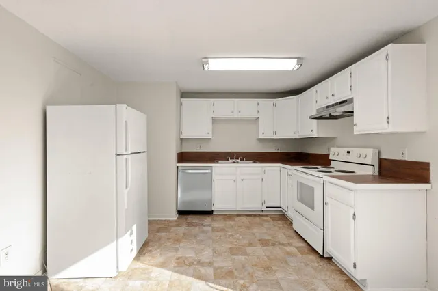 a kitchen with stainless steel appliances a refrigerator sink and white cabinets