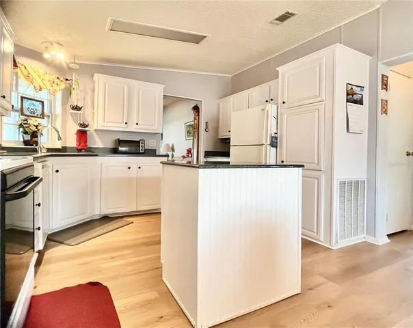 a kitchen with white cabinets and refrigerator