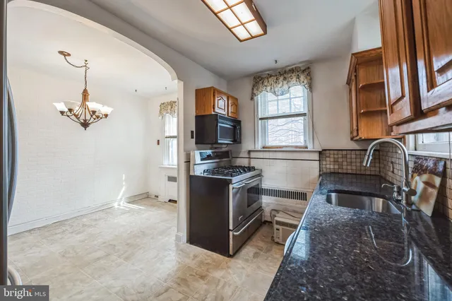 a kitchen with stainless steel appliances granite countertop a stove a sink dishwasher a refrigerator and a dining table with wooden floor