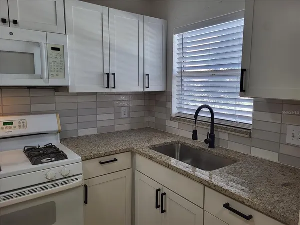 a kitchen with stainless steel appliances granite countertop a sink stove and cabinets