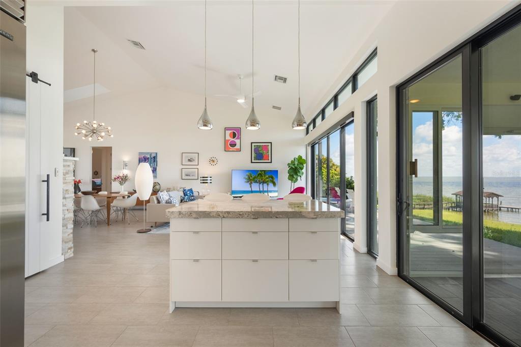 17640 Broad Street Montverde, FL 34756 - Photo 11 of 48 a kitchen with kitchen island a large counter top space a flat screen tv and a view of living room