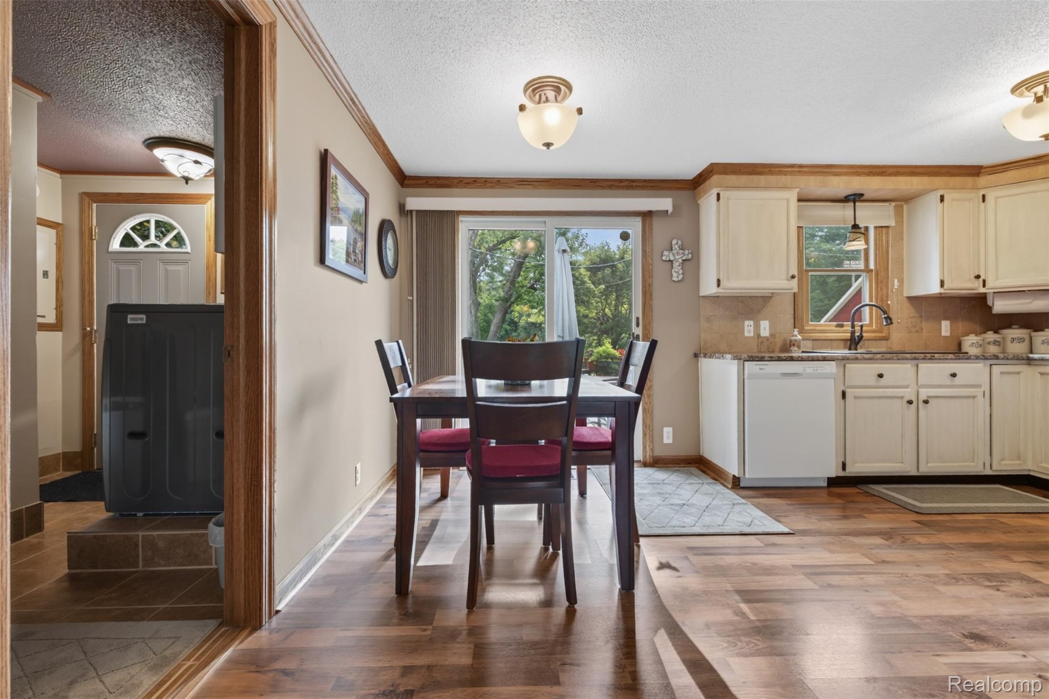 5977 Anglers Road Ortonville, MI 48462 - Photo 7 of 63 Kitchen and dining area featuring wood-finish flooring, cream cabinetry, a tile backsplash, and sliding glass door access to the exterior
