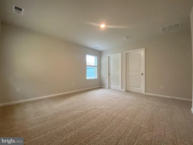 a view of an empty room with window and closet area