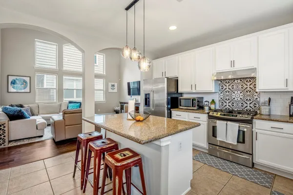 a open kitchen with stainless steel appliances granite countertop a stove top oven a sink dishwasher and white cabinets with wooden floor