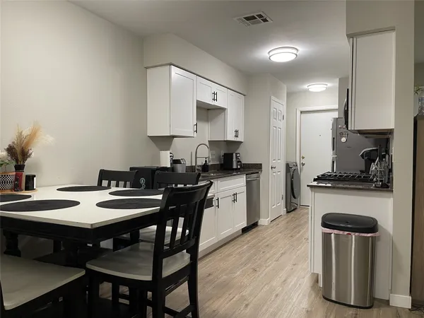 a kitchen with a dining table chairs and white cabinets