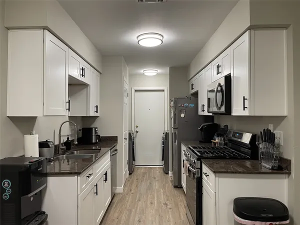 a kitchen with granite countertop a sink a stove and refrigerator