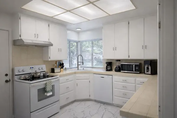 a kitchen with white cabinets appliances and a sink
