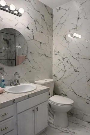 a bathroom with a granite countertop toilet sink and mirror