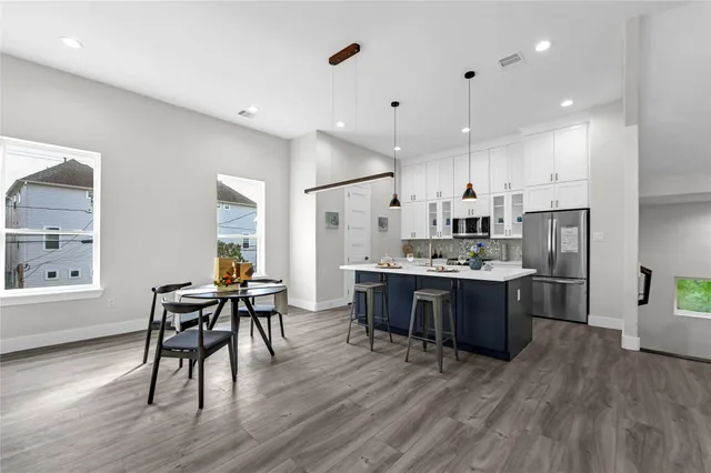 a living room with stainless steel appliances kitchen island granite countertop wooden floor a dining table and chairs