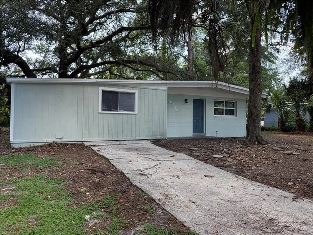 a backyard of a house with large trees and wooden fence