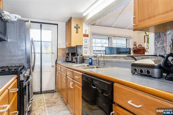 a kitchen with stainless steel appliances granite countertop a sink a stove cabinets counter space and a window