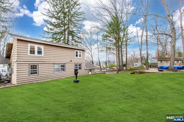 a backyard of a house with plants and large tree