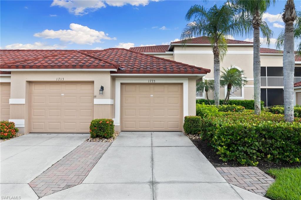 2870 Cypress Trace Circle, Unit 1723 Naples, FL 34119 - Photo 23 of 33 a front view of a house with a yard and garage