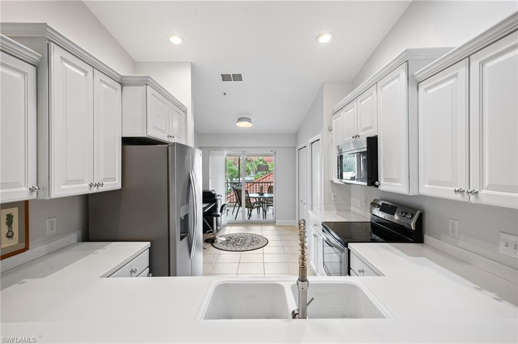2870 Cypress Trace Circle, Unit 1723 Naples, FL 34119 - Photo 8 of 33 a kitchen with stainless steel appliances a refrigerator and a stove top oven