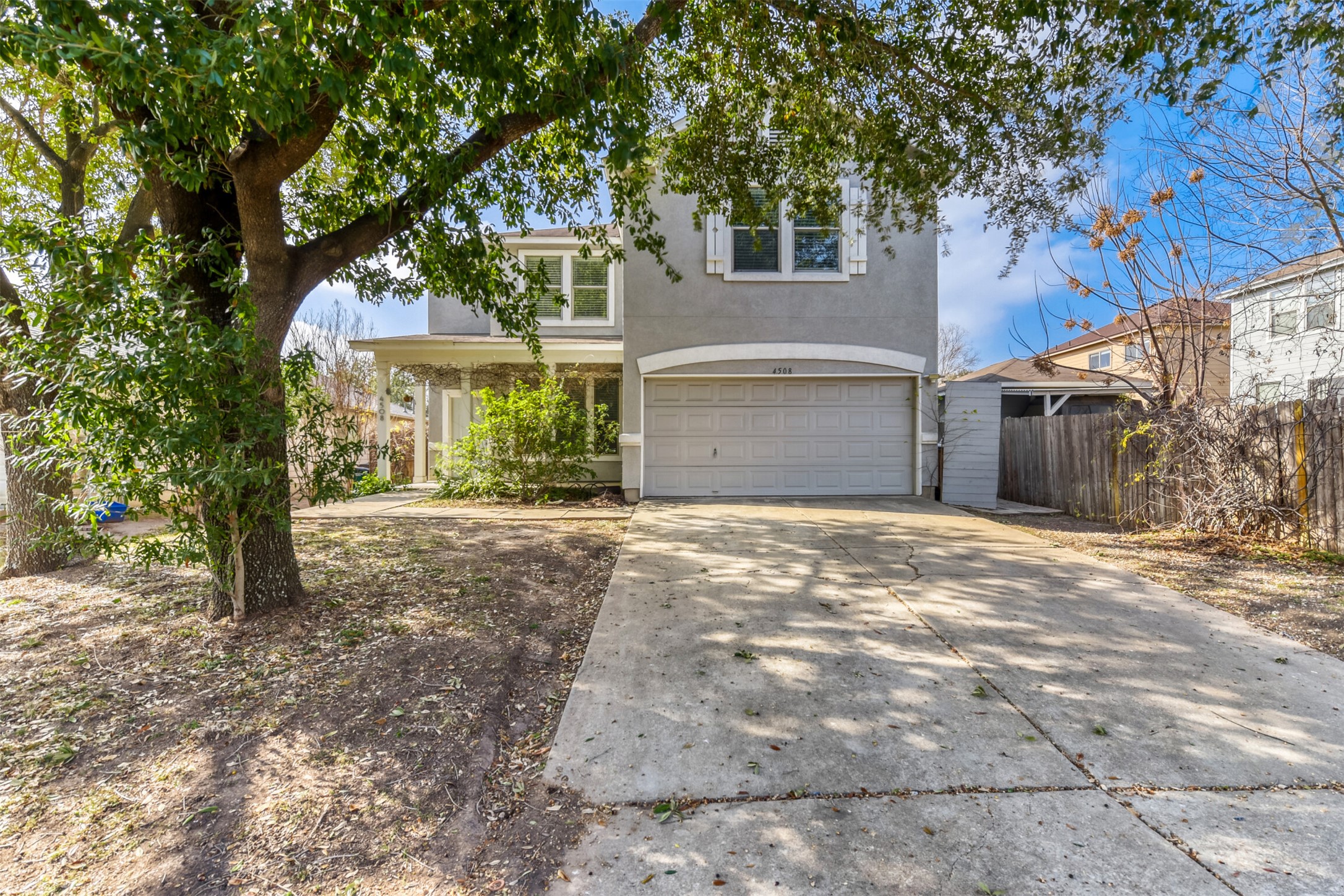 4508 Peach Grove Road Austin, TX 78744 - Photo 23 of 24 Traditional home with driveway, an attached garage, stucco siding, and a porch