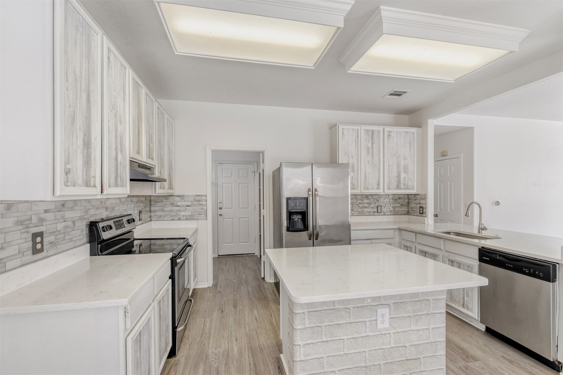 4508 Peach Grove Road Austin, TX 78744 - Photo 8 of 24 Kitchen featuring appliances with stainless steel finishes, backsplash, a peninsula, and light wood-style floors