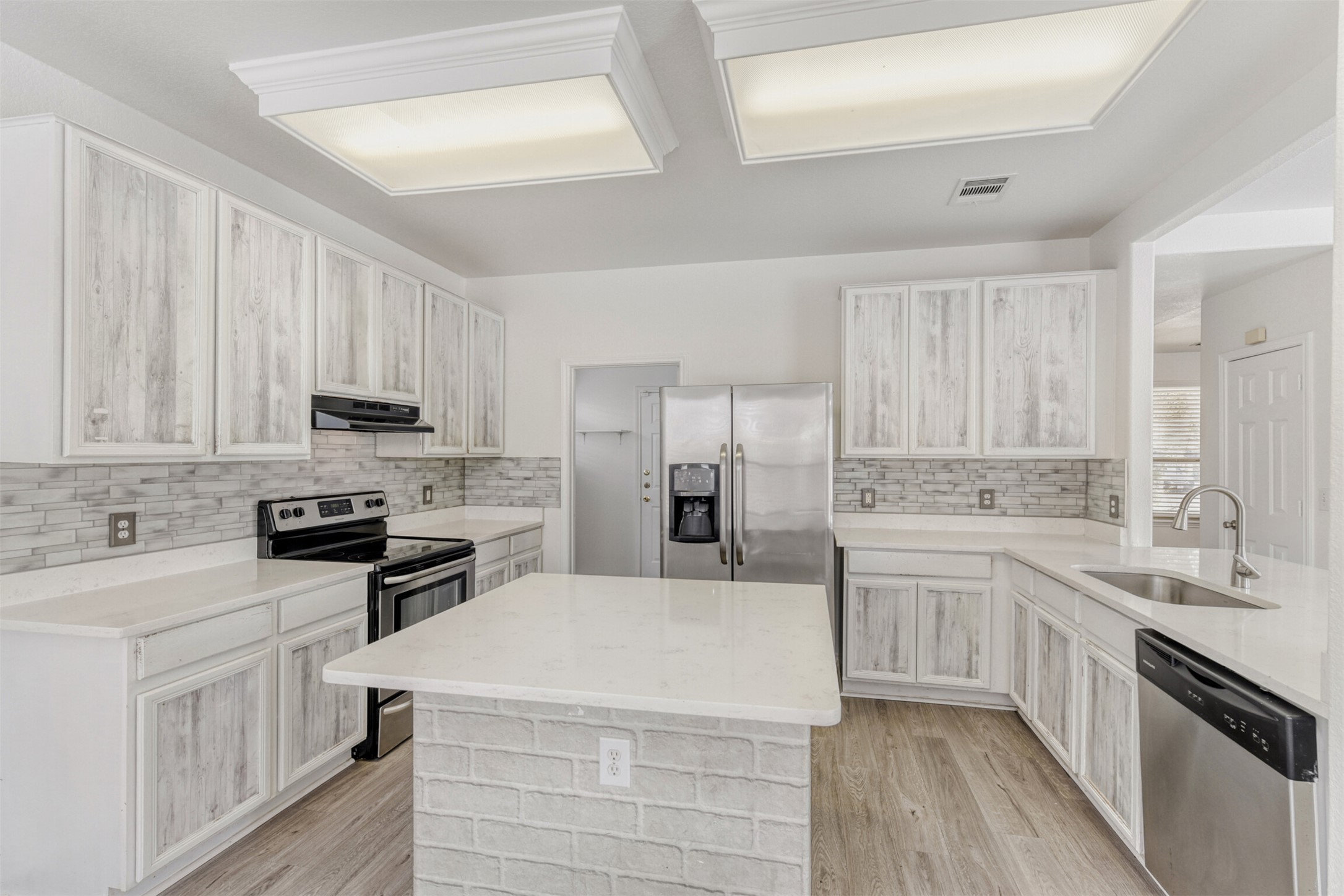 4508 Peach Grove Road Austin, TX 78744 - Photo 9 of 24 Kitchen with stainless steel appliances, tasteful backsplash, light wood-style floors, and light stone counters