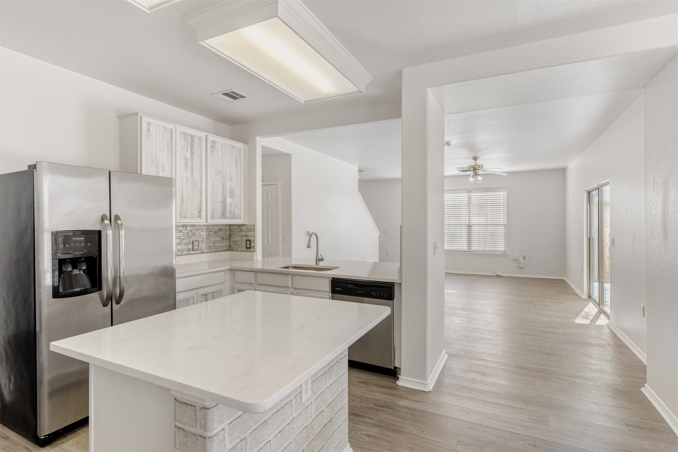 4508 Peach Grove Road Austin, TX 78744 - Photo 24 of 24 Kitchen featuring appliances with stainless steel finishes, white cabinetry, open floor plan, and a center island
