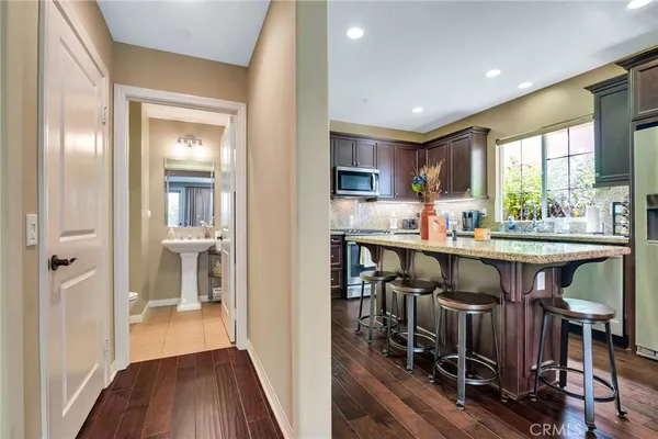 a kitchen with stainless steel appliances granite countertop wooden cabinets a sink a stove a dining table and chairs