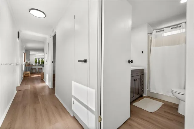 a view of a hallway with wooden floor and a bathroom